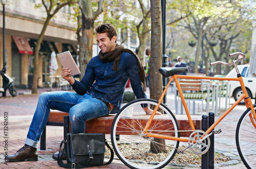 Happy, city and smile with man, tablet and bicycle with adventure and digital app with email and social media. Person on bench, outdoor and New York with guy and technology with connection and typing