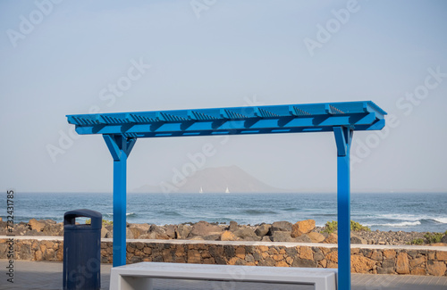 Banco en la orilla del Océano Atlántico con el Islote de Lobos de fondo, Fuerteventura, Islas Canarias photo