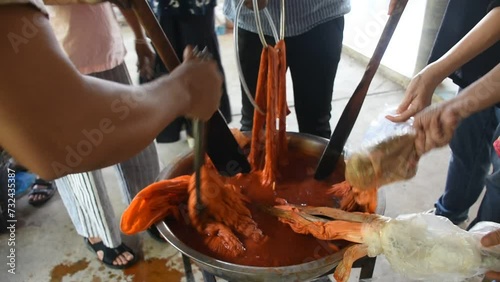 Thai craftsmanship artist working batik ikat and tie dye natural orange color from boil Bixa orellana achiote in handmade handicrafts studio in Baan Phu Chuang at Ban Rai city in Uthai Thani, Thailand photo