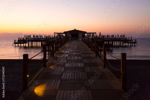 Early dark morning over sea pier is barely lit by the first rays of the sun and electric lamps. © ALEXEY