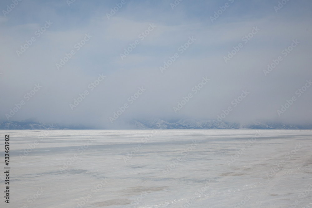 Landscape with mountains in the haze and  ice of Lake Baikal.