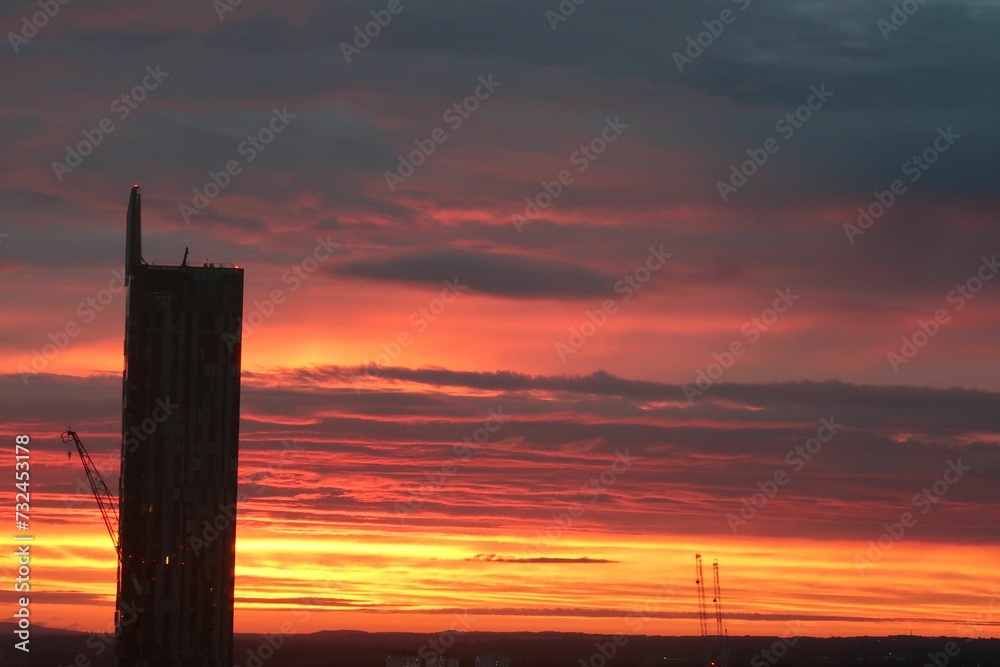 Sunset skyline featuring a dramatic silhouette of a building against a vibrant orange sky Sunset skyline featuring a dramatic silhouette of a building against a vibrant orange sky