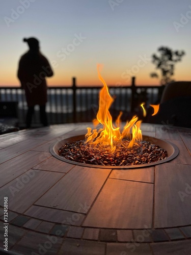 Obraz na plátně Closeup of a flickering fire pit on a wooden deck with a blurry background