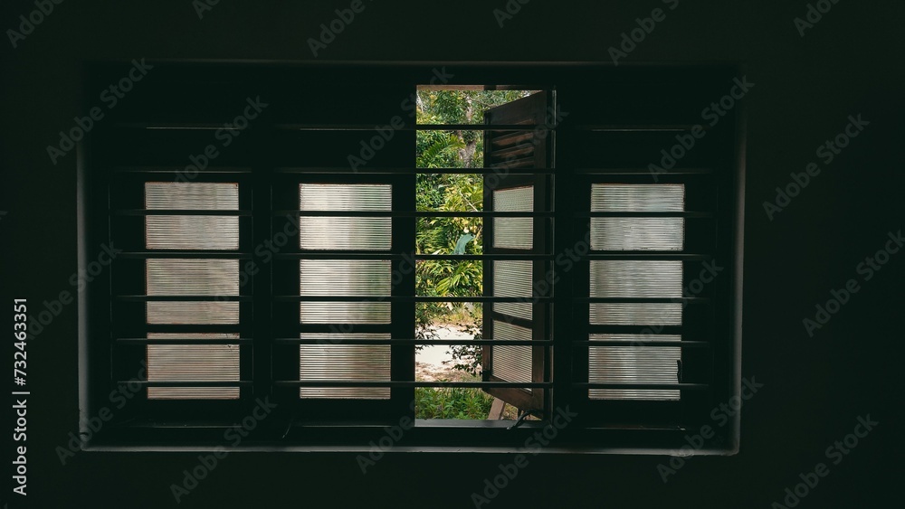 Fototapeta premium Window with its blinds open, surrounded by lush greenery