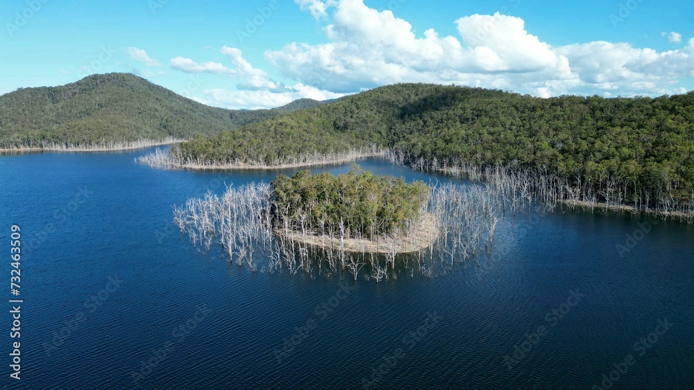 Naklejka premium Scenic aerial view of a tranquil lake surrounded by lush green hills, creating a tranquil atmosphere
