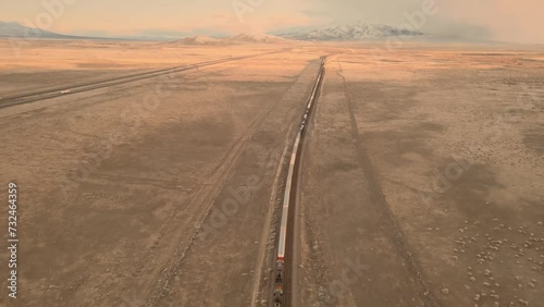 Aerial of a long train alongside the highway in the middle of a desert photo
