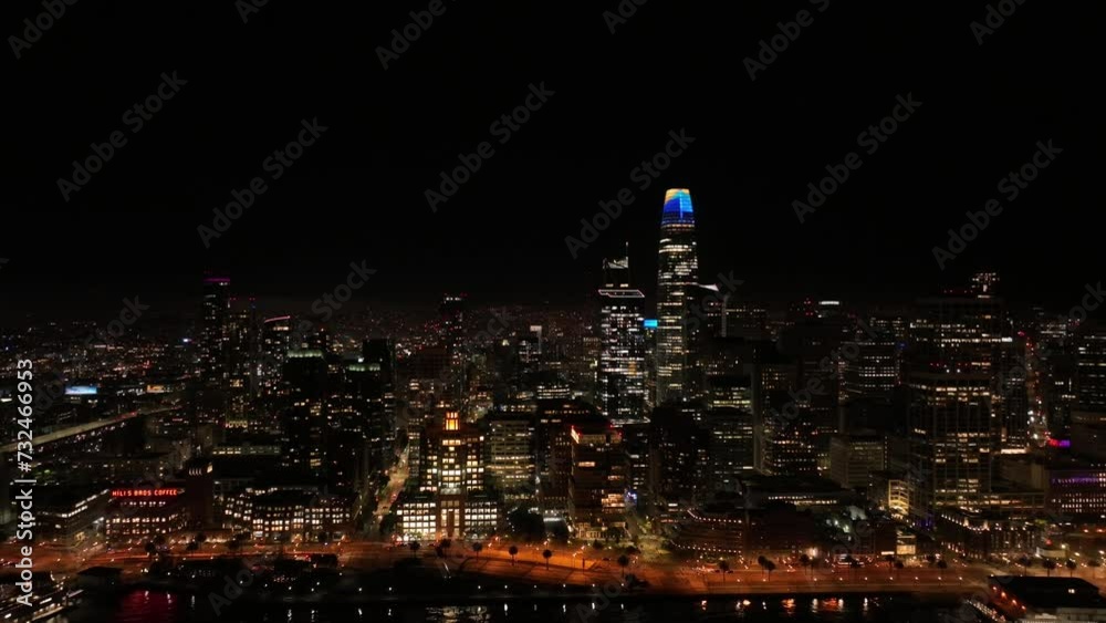 Drone view of an illuminated cityscape on a waterfront during nighttime