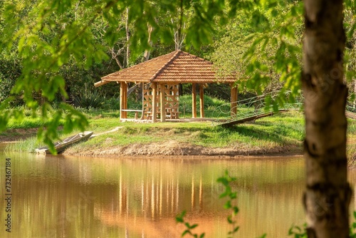a small gazebo near the water surrounded by trees and grass