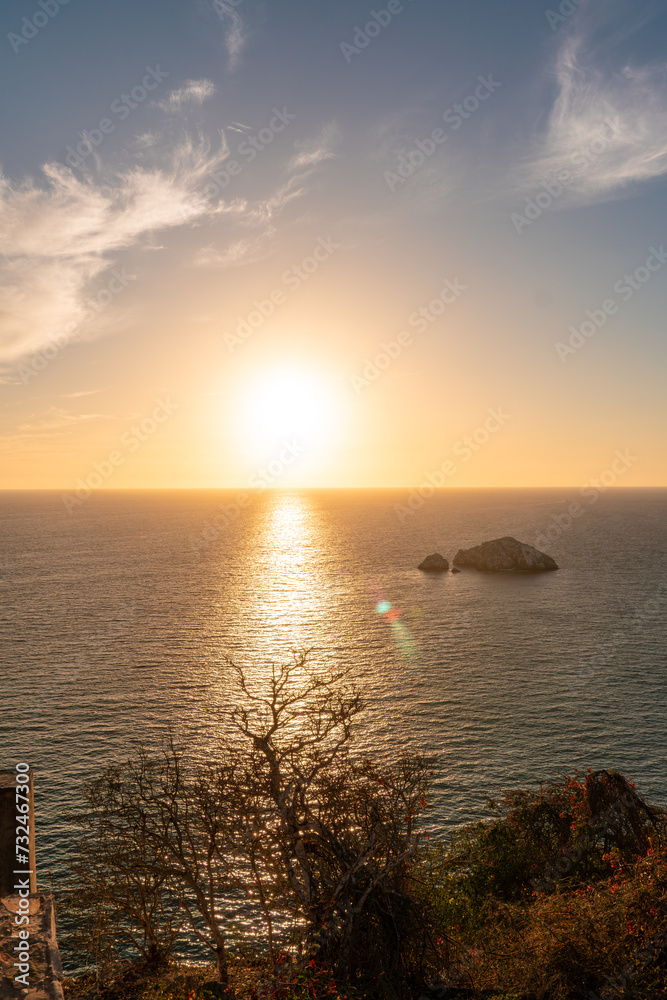 the sun sets behind a hill overlooking the ocean in the background