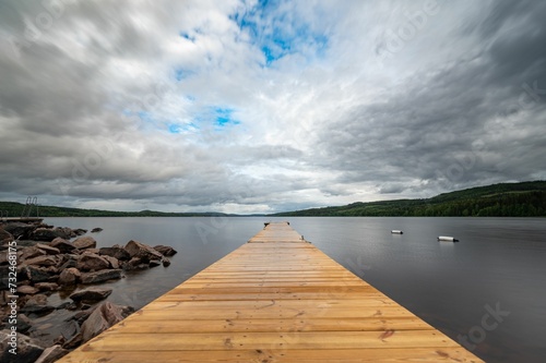 Dock with several small against the background of a tranquil lake and cloudy sky.