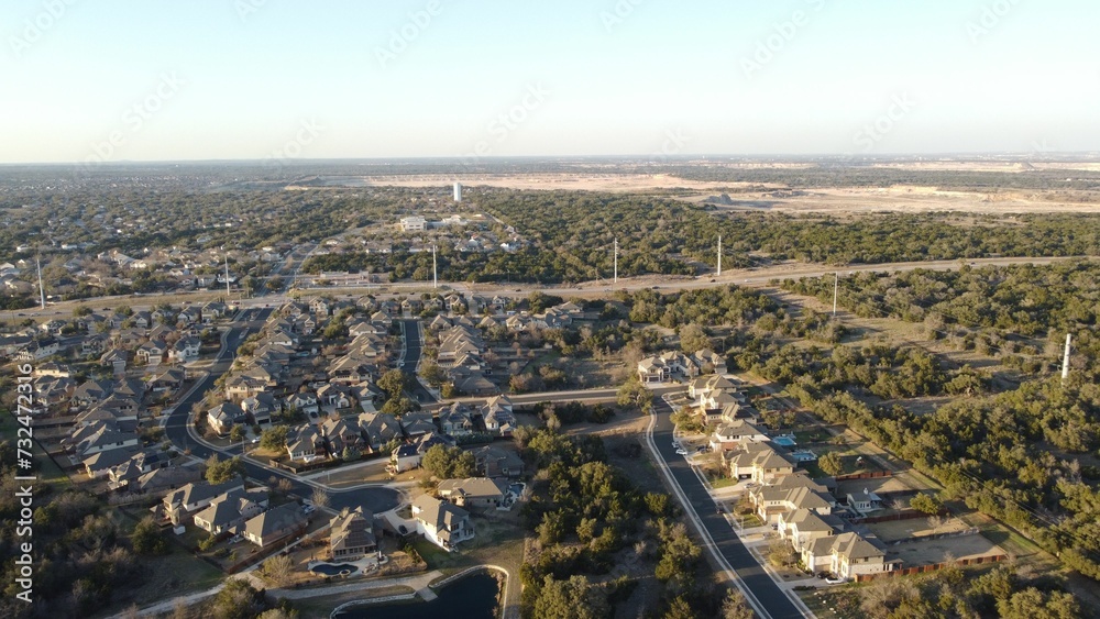 Aerial view of houses and roads on green hills on a sunny day