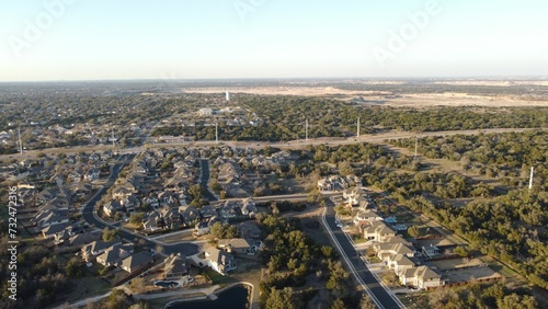 Aerial view of houses and roads on green hills on a sunny day