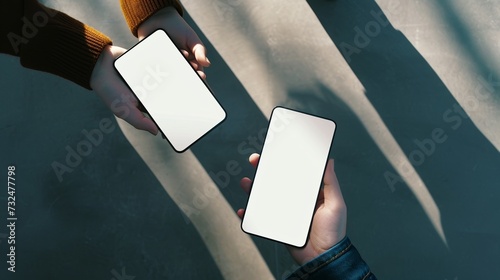 Two people exchanging contact information over smartphones with blank screens