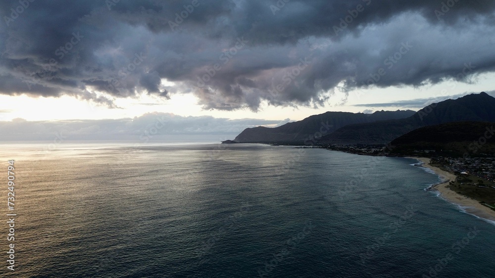 Drone view of sea waves surrounded by cliffs under a cloudy sky in the evening