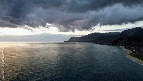 Drone view of sea waves surrounded by cliffs under a cloudy sky in the evening
