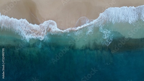 Aerial view of sea waves crashing against a beach in the daylight © Wirestock
