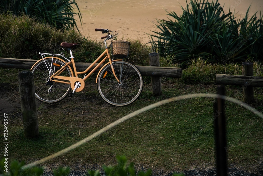Beige bicycle parked on a wooden post near a sandy beach