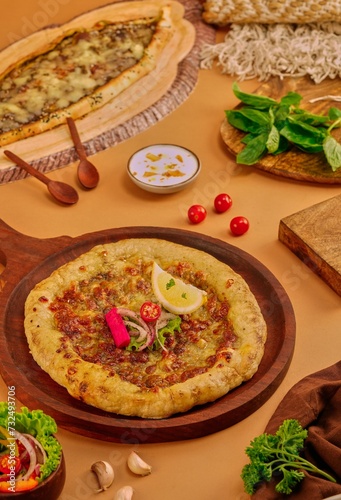 Close-up of lahmajo on a wooden board with a lemon slice garnish