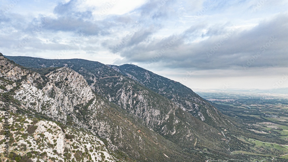 Obraz premium Majestic mountain peak overlooks a vast valley filled with lush green fields