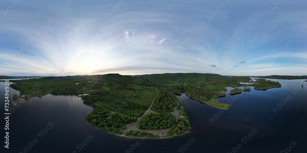 Panoramic shot of a lake surrounded by greenery in the countryside