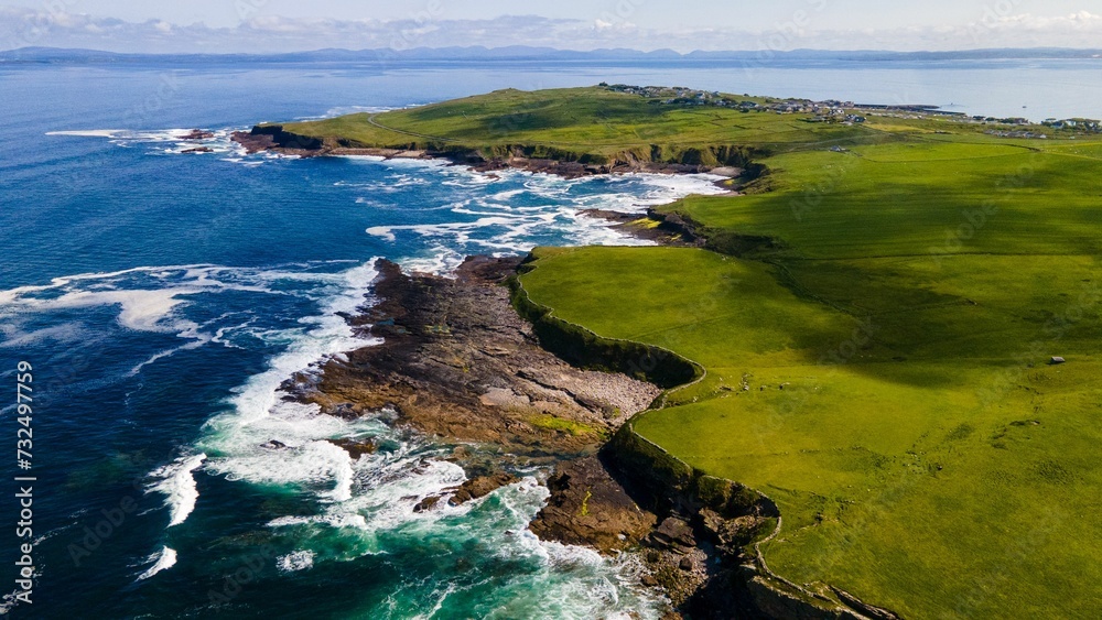 Fototapeta premium Aerial view of sea waves against the green coastline