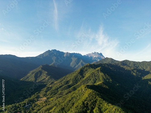 Aerial view of a mountain range covered with green forests on a sunny day