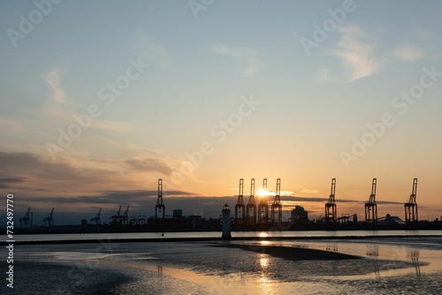 Majestic view of construction machinery silhouetted against a sunset in Liverpool © Wirestock