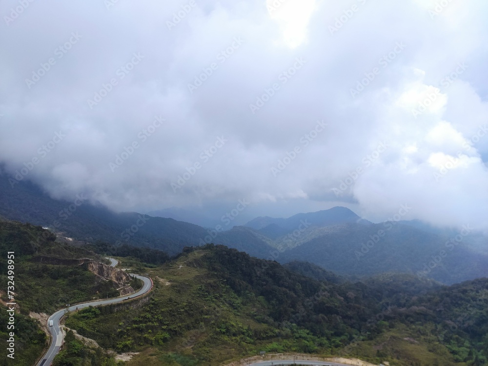 Aerial view of a road in green mountains on a cloudy day