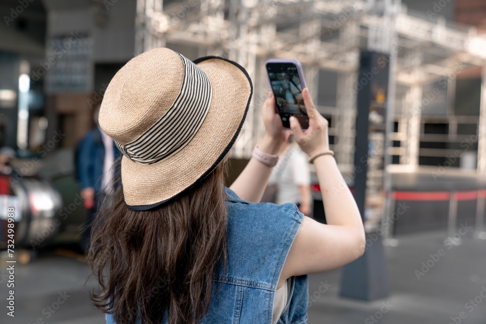 Young female in a straw hat, taking photos with her phone