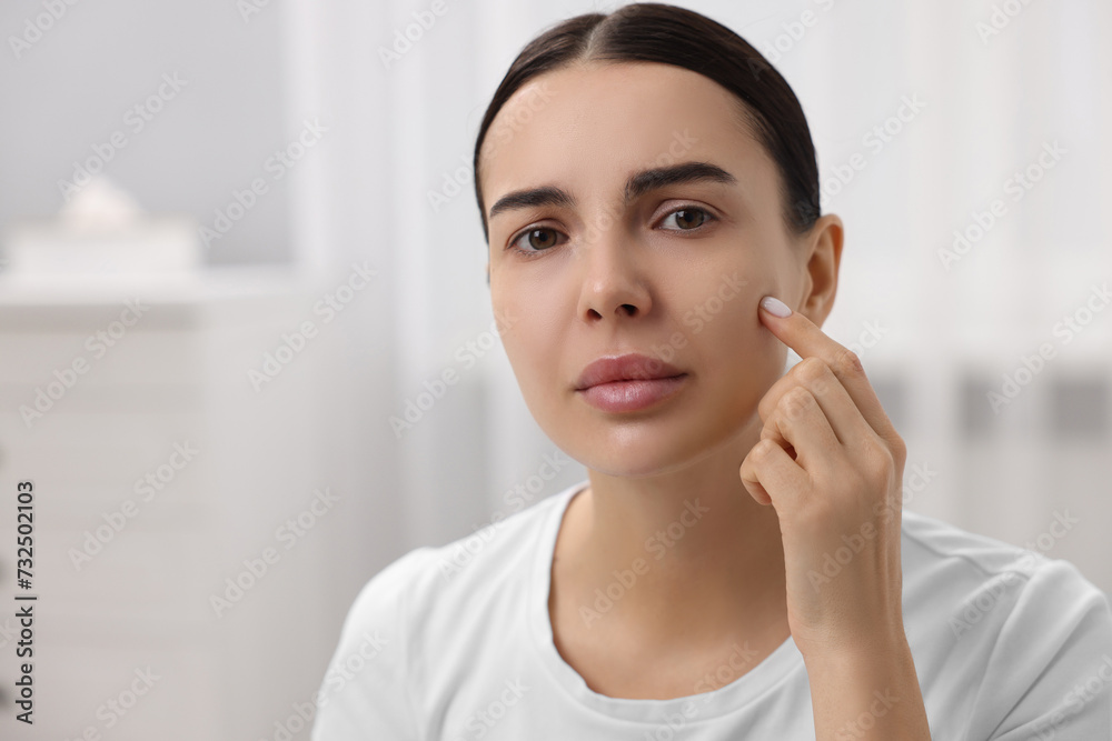Woman with dry skin checking her face indoors, space for text Woman with dry skin checking her face indoors, space for text