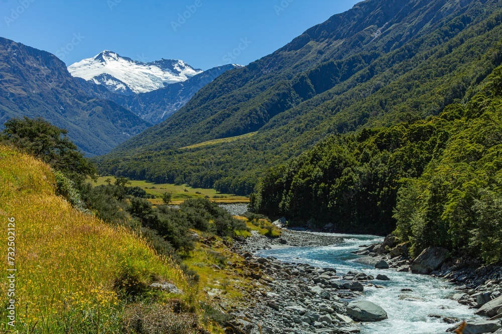 a river runs down the slope next to a lush green hill