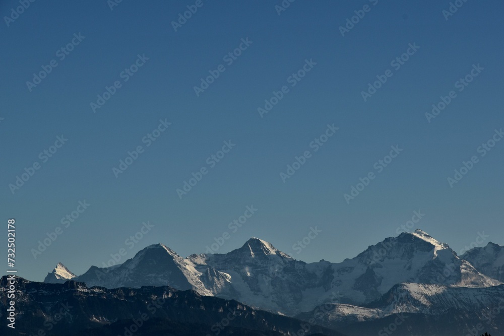 a plane flying over a snow covered mountain side line under the blue sky