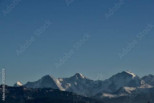 a plane flying over a snow covered mountain side line under the blue sky