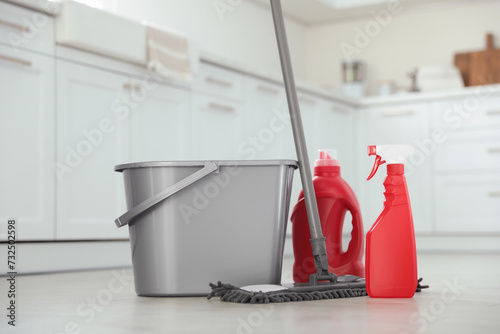 Mop, detergents and plastic bucket in kitchen. Cleaning supplies
