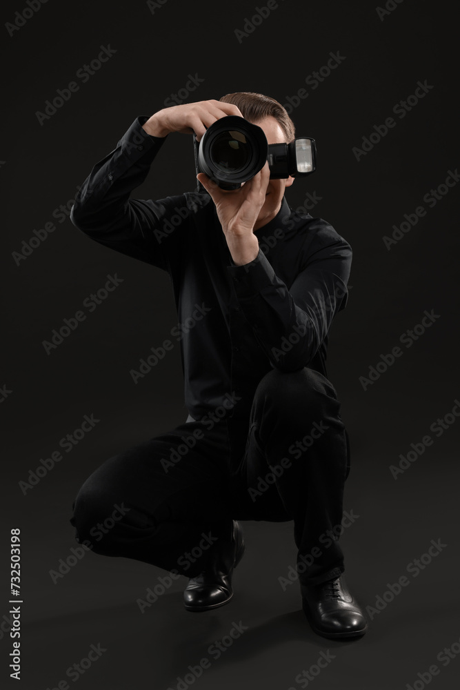 Professional photographer taking picture on black background