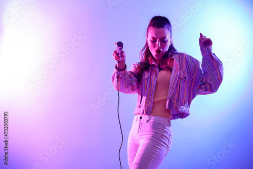 Beautiful singer with microphone performing on bright background. Space for text