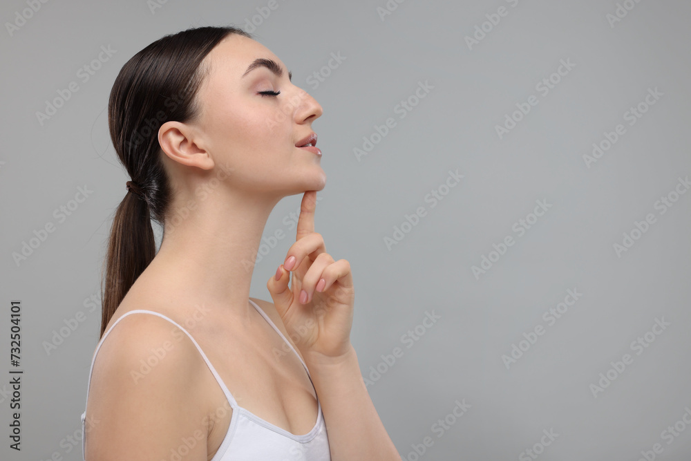 Beautiful woman touching her chin on grey background. Space for text Beautiful woman touching her chin on grey background. Space for text