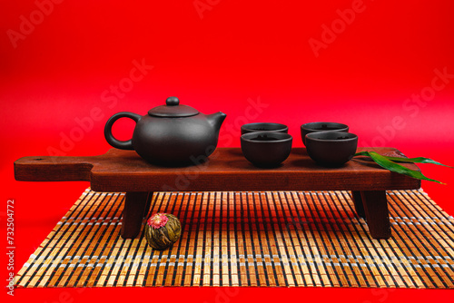 Black teapot and cups with bamboo leaves on a tray. Traditional tea ceremony.