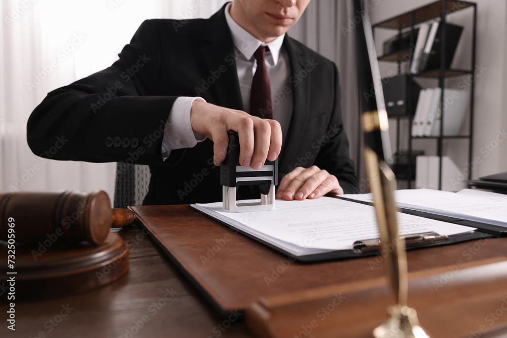 Notary stamping document at wooden table in office, closeup Notary stamping document at wooden table in office, closeup
