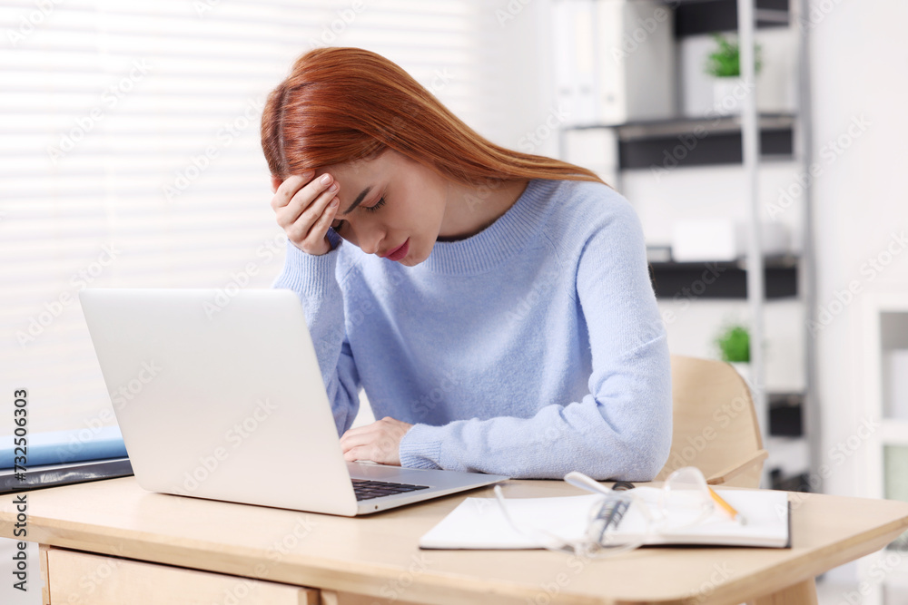 Woman suffering from headache at workplace in office Woman suffering from headache at workplace in office