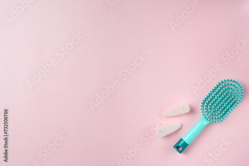 Blue hairbrush with pearl pins on a pink background. Copy space.