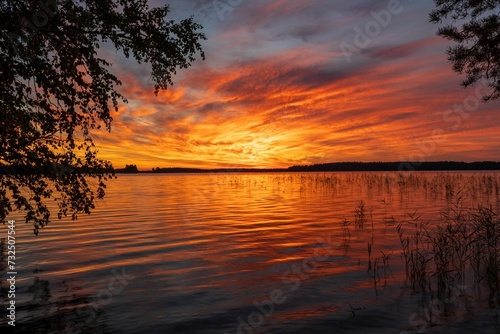 Beautiful and tranquil lake with lush grassy terrain and a stunning sunset sky.