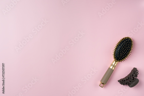 Hairbrush and hairpin on a pink background. Copy space