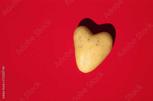 Heart shaped potato on bright red background