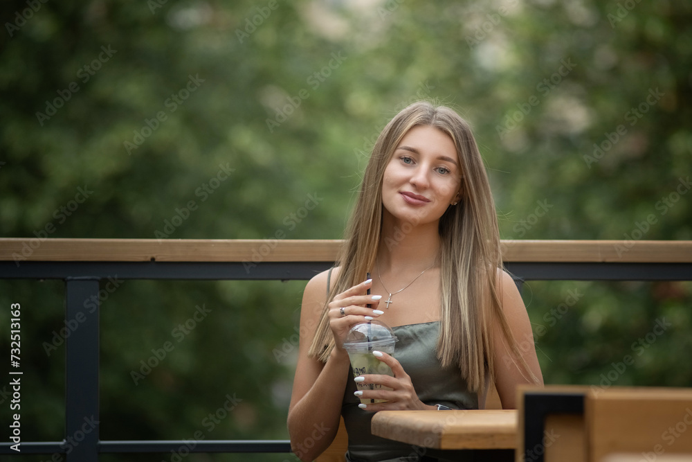 Portrait of a young beautiful blonde girl in a city summer park.