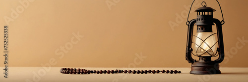 Empty panoramic header with traditional ornamental Arabic lantern and Muslim rosary praying beads in a studio on golden background with copy space for greeting text. Ramadan Kareem wallpaper