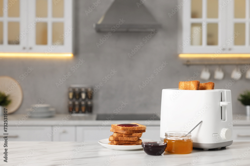 Making toasts for breakfast. Appliance, crunchy bread, honey and jam on white table in kitchen. Space for text Making toasts for breakfast. Appliance, crunchy bread, honey and jam on white table in kitchen. Space for text