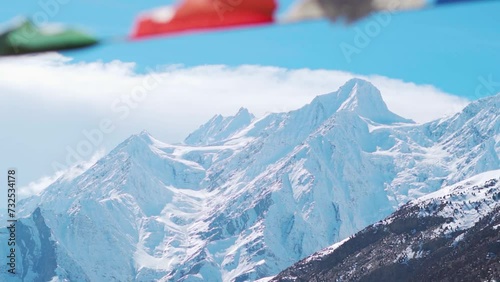 Defocused Buddhist Prayer flags waving in the wind in front of snow covered Himalayan mountains during the winter season at Keylong in Himachal Pradesh, India. Selective focus on the mountains.