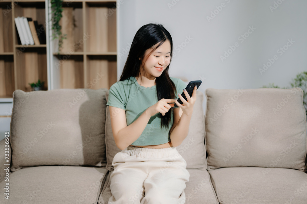 Asian woman using the smartphone and tablet on the sofa at home Asian woman using the smartphone and tablet on the sofa at home