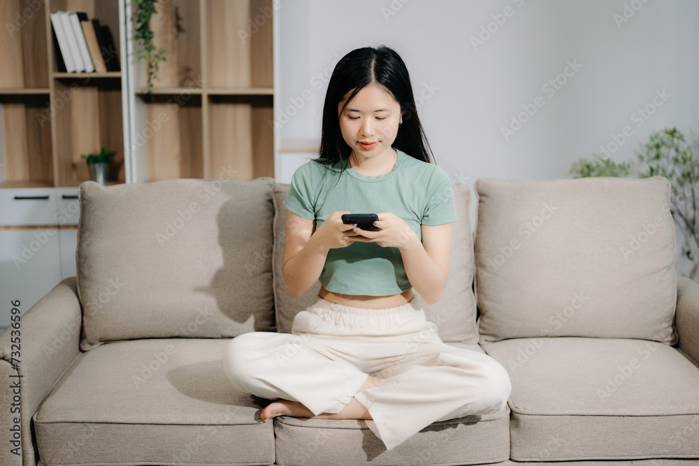 Asian woman using the smartphone and tablet on the sofa at home Asian woman using the smartphone and tablet on the sofa at home